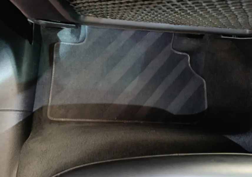 Vue rapprochée du tapis de sol noir côté passager arrière d’un Audi Q5 gris clair hybride rechargeable 2023.