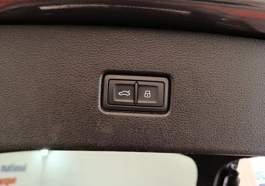 Boutons d'ouverture de coffre et de verrouillage intégrés dans le panneau intérieur du hayon d'un Audi Q5 gris clair 2023 hybride rechargeable.