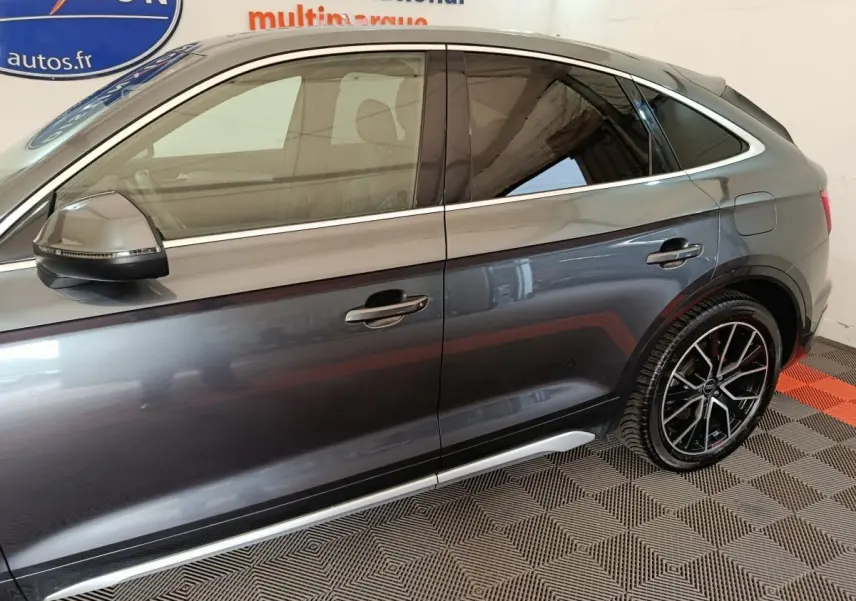 Vue de profil côté gauche d'un Audi Q5 gris clair 2023 avec jantes noires au design sportif.