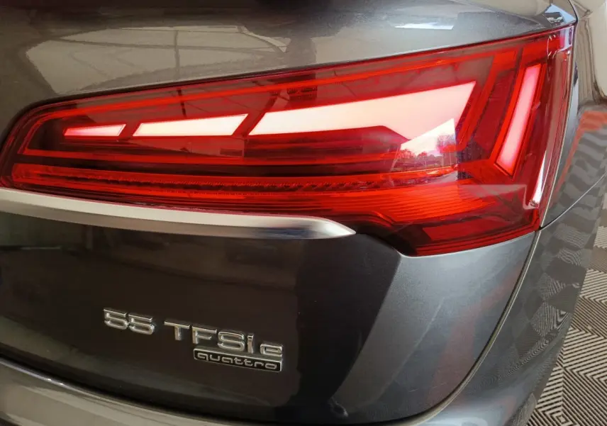 Gros plan sur le feu arrière droit d’un Audi Q5 gris clair 2023 avec badge 55 TFSI e quattro visible.