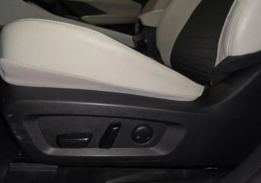 Gros plan sur les commandes électriques du siège avant droit en cuir clair et tissu noir du Nissan Qashqai 2024 gris.