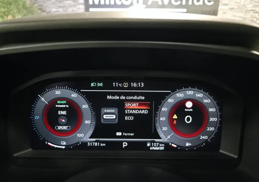 Tableau de bord numérique du Nissan Qashqai gris, affichant le mode de conduite Sport à 16h13.