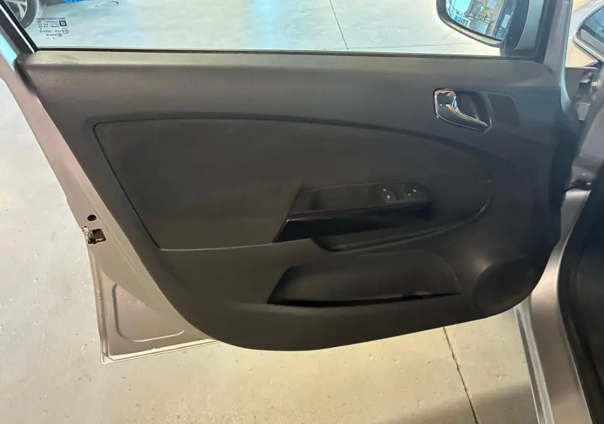 Vue intérieure de la porte avant gauche gris clair de l’Opel Corsa 1.2i 85 Edition avec garniture noire et commandes de vitres.