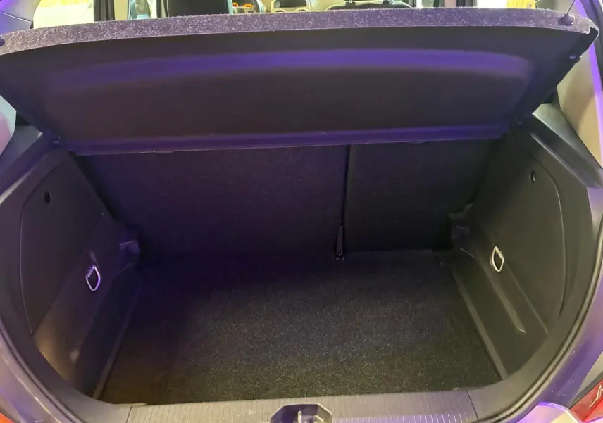 Coffre ouvert de l’Opel Corsa gris clair 5 portes, vue arrière montrant l’espace de rangement et la moquette noire.