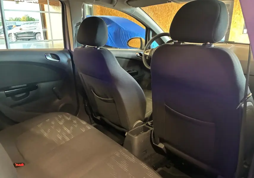 Vue intérieure arrière de l'Opel Corsa 2012 avec sièges en tissu noir et portes arrière visibles côté gauche.