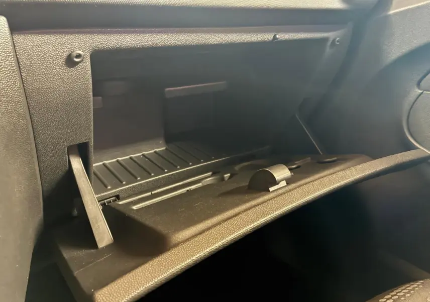 Coffre à gants ouvert de l’Opel Corsa 1.2i 85 Edition 2012 avec intérieur noir en tissu, vue de face côté passager.
