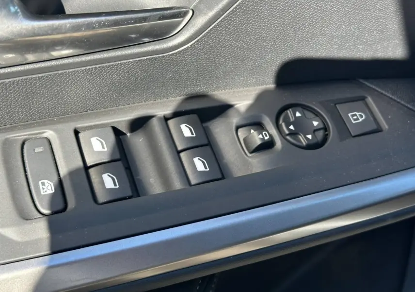 Gros plan sur les commandes de vitres et rétroviseurs côté conducteur du Peugeot 5008 Hybrid blanc Okénite.