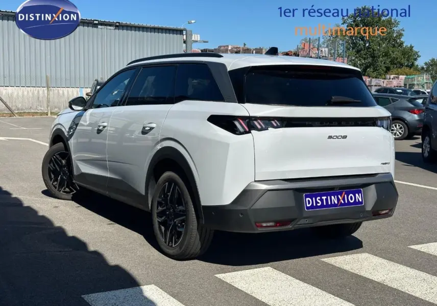 Vue 3/4 arrière droite d’un Peugeot 5008 Hybrid blanc Okénite avec vitres surteintées et jantes noires.