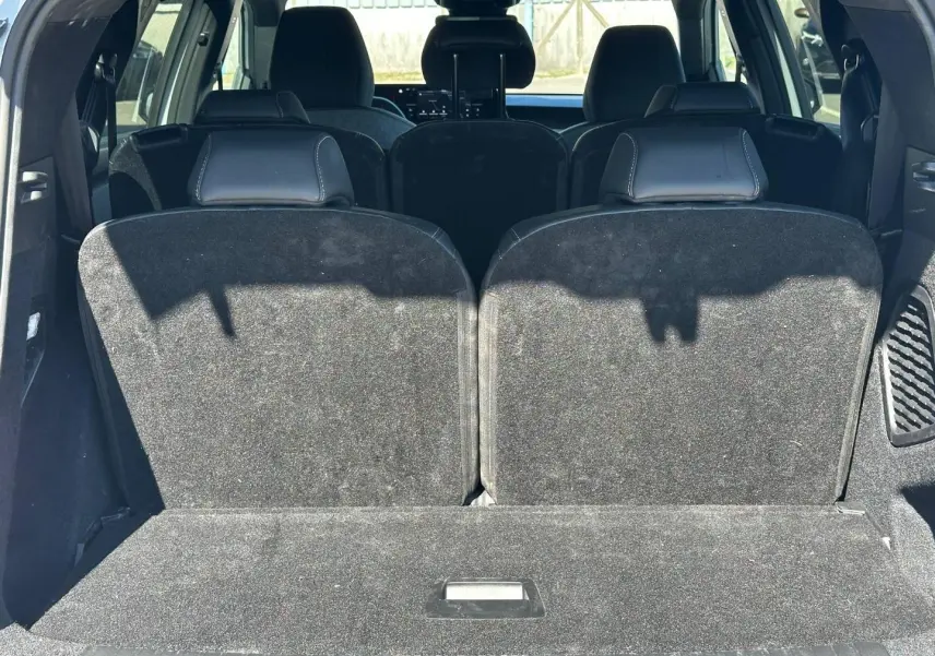 Vue arrière du coffre du Peugeot 5008 Hybrid blanc avec les sièges rang 3 relevés en tissu noir.