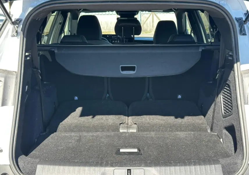 Coffre ouvert du Peugeot 5008 blanc Okénite, vue arrière montrant les sièges arrière rabattus et la plage arrière.