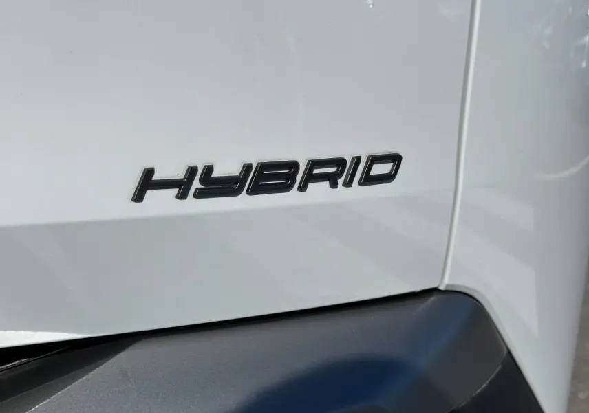 Gros plan sur l’inscription Hybrid en noir sur la carrosserie blanche Okénite d’un Peugeot 5008 2025.