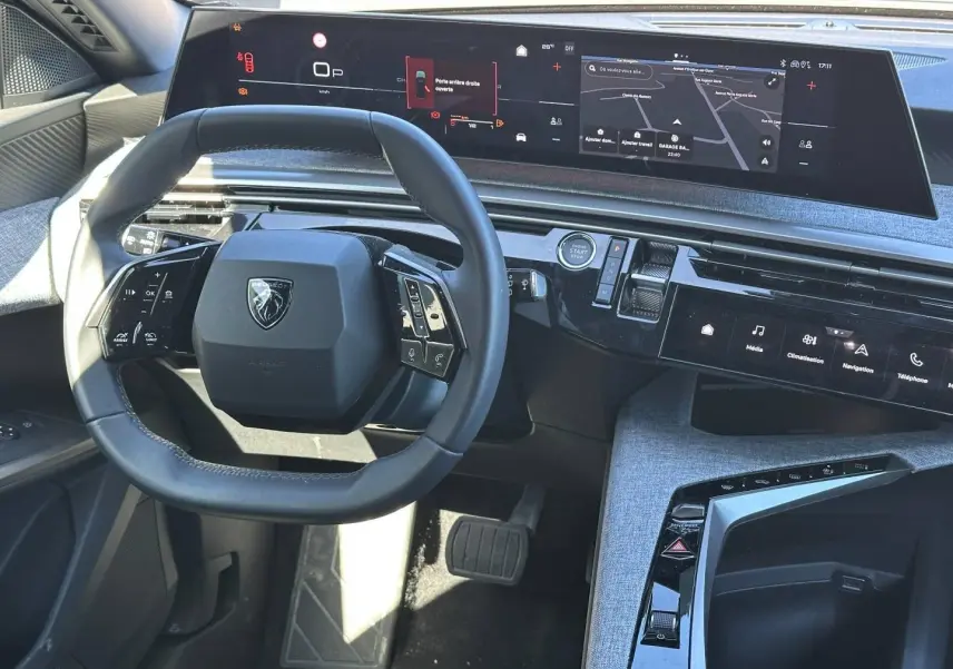 Vue intérieure du tableau de bord et volant cuir multifonction du Peugeot 5008 Hybrid 2025 avec écran tactile panoramique.