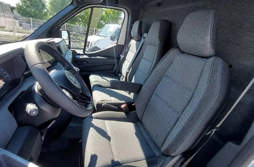 Vue intérieure côté conducteur du Nissan Interstar Fourgon 2025, sièges gris et tableau de bord moderne.