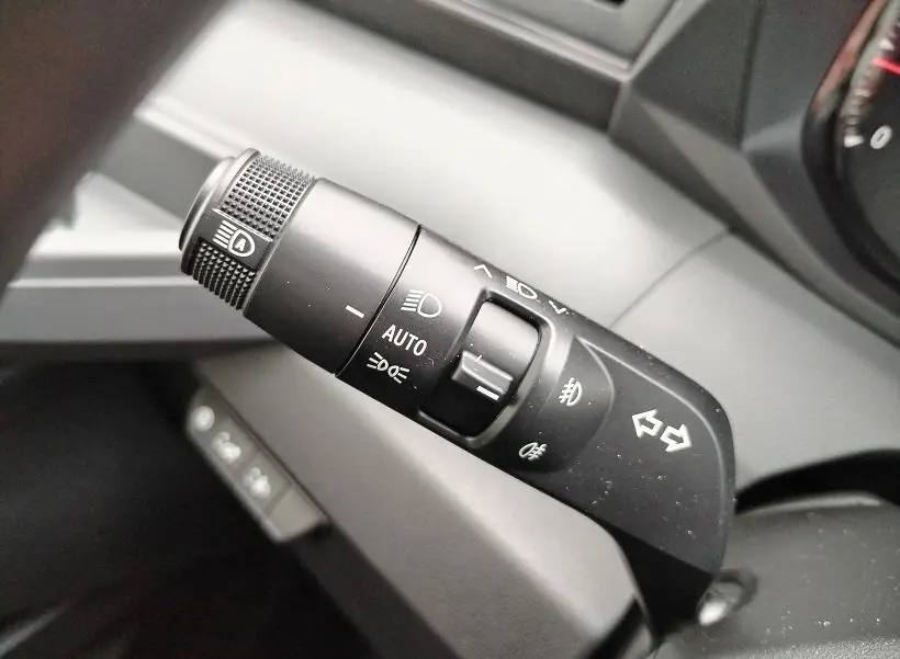 Gros plan sur la commande des phares et clignotants noire à l'intérieur du Nissan Interstar Fourgon blanc.
