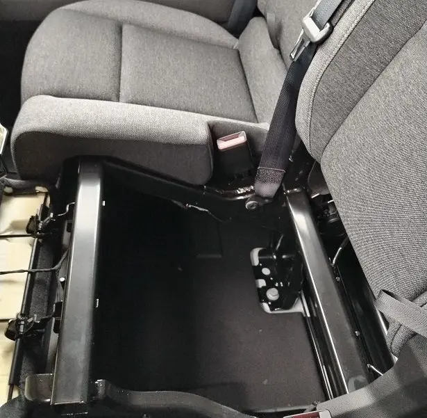Vue rapprochée de l'intérieur côté passager du Nissan Interstar Fourgon 2026, siège gris avec rangement sous l'assise ouvert.