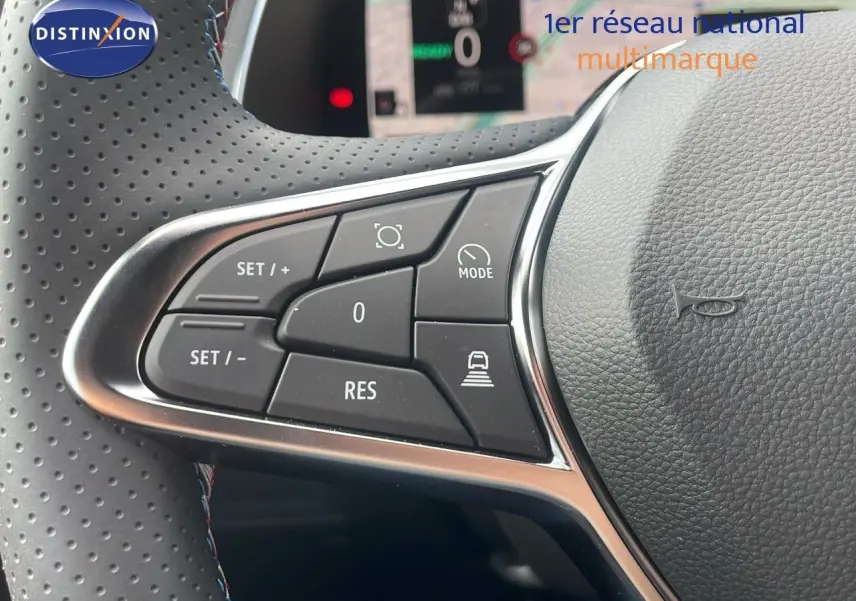 Gros plan sur les commandes au volant du Renault Captur E-Tech hybride 2025, cuir noir perforé avec surpiqûres tricolores.