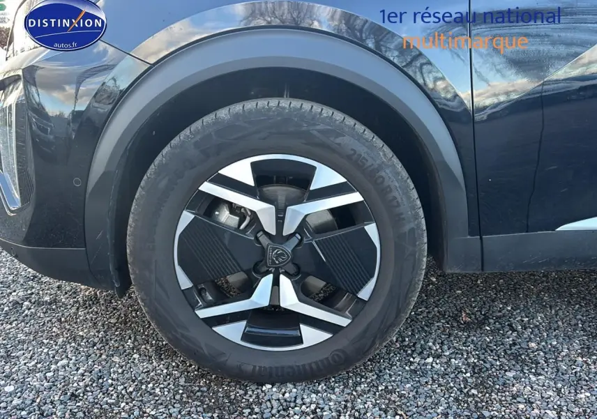 Gros plan sur la roue avant gauche noire du Peugeot 2008 1.2 hybrid 145 allure e-dcs6 avec jante alu distinctive.