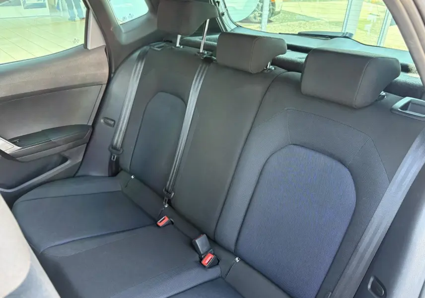 Vue intérieure de la banquette arrière noire du SEAT Arona 2024 avec trois appuie-tête et ceintures de sécurité visibles.