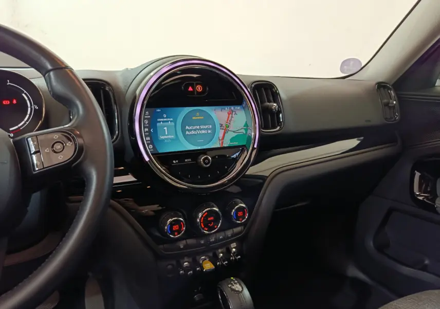 Vue intérieure côté conducteur du tableau de bord noir du MINI Countryman avec écran tactile circulaire et commandes digitales.
