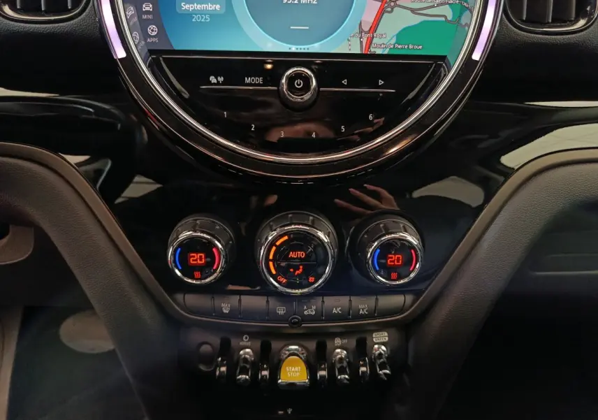 Gros plan sur la console centrale du MINI Countryman blanc, mettant en valeur les commandes de climatisation et l’écran tactile rond.