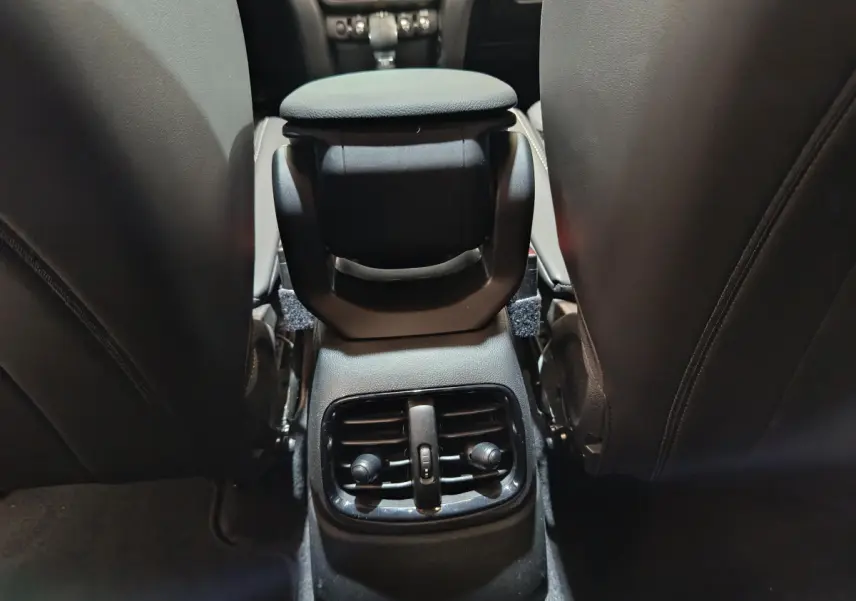 Vue intérieure arrière du MINI Countryman blanc, concentrée sur la console centrale avec bouches d'aération et accoudoir noir.