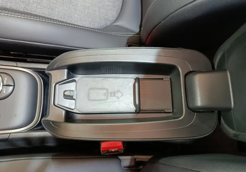 Vue plongeante sur le rangement central noir du MINI Countryman blanc, avec compartiment à clé et accoudoir en cuir.