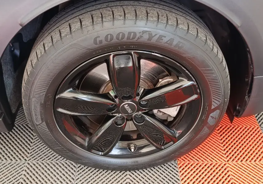 Gros plan sur la roue avant droite noire brillante d'une MINI Countryman blanche, pneu Goodyear visible.