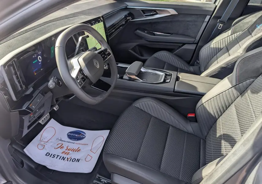 Vue intérieure côté conducteur du Renault Austral gris métallisé, avec sellerie mixte Alcantara et volant textile spécifique.