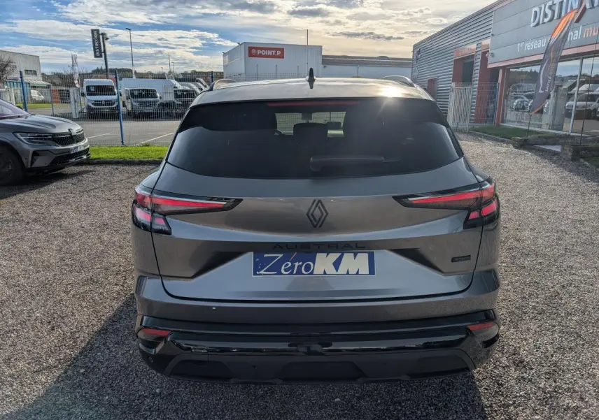 Vue arrière d'un Renault Austral gris métallisé avec toit noir étoilé et feux LED fins, stationné sur un sol gravillonné.