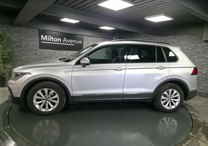 Volkswagen Tiguan gris métallisé vu de profil côté gauche dans un showroom avec jantes alliage 17 pouces.