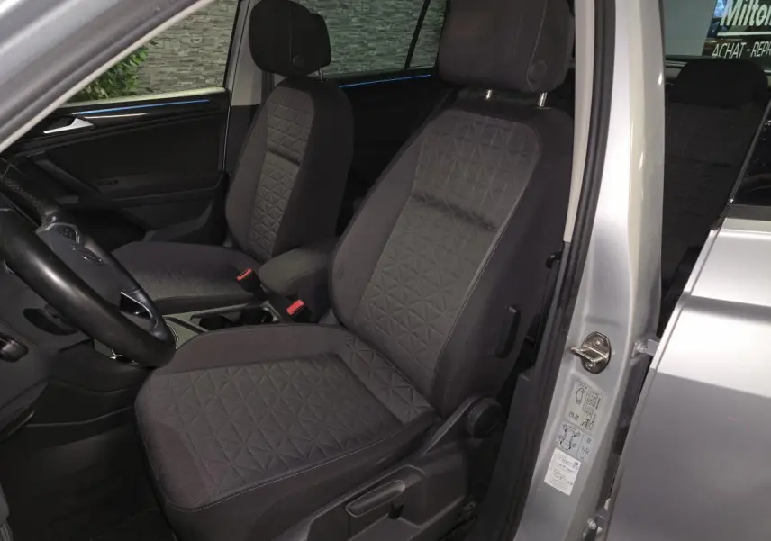 Vue intérieure côté conducteur du Volkswagen Tiguan gris 2023, sièges tissu noir avec motifs géométriques.