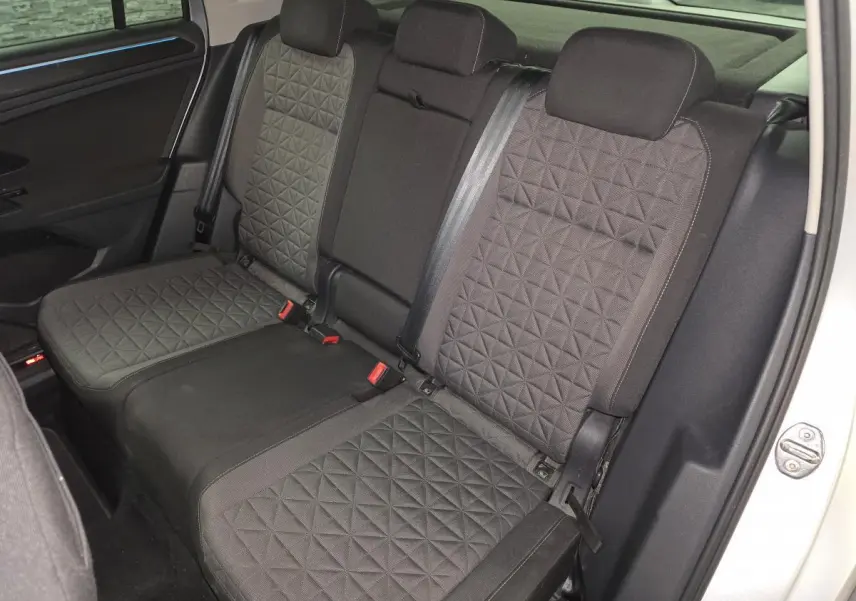 Vue intérieure des sièges arrière en tissu gris à motif géométrique du Volkswagen Tiguan 2023, avec ceinture de sécurité visible.