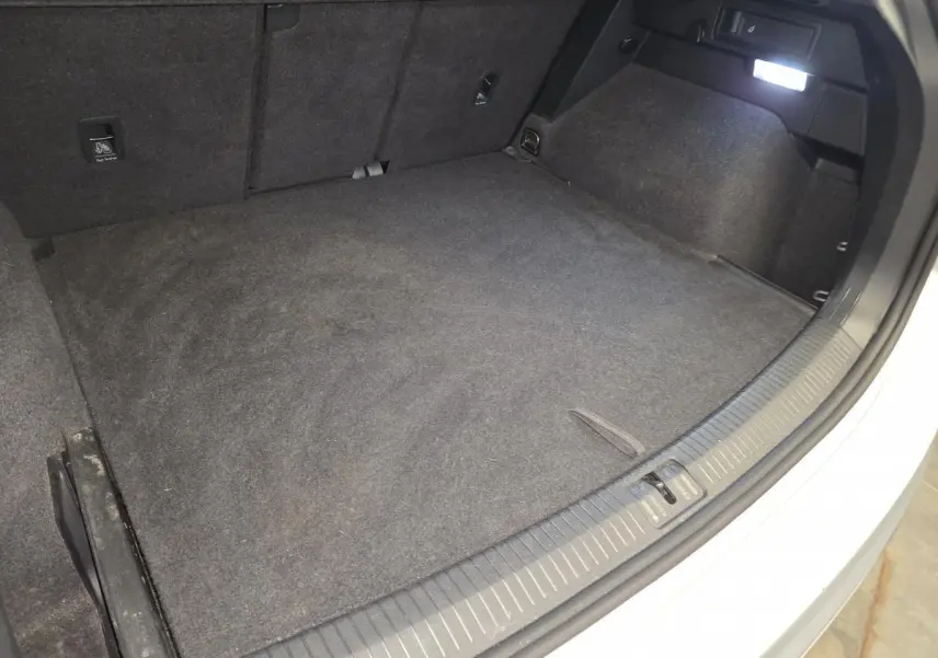 Coffre ouvert du Volkswagen Tiguan gris, vue plongeante montrant l'espace de chargement et la moquette intérieure.
