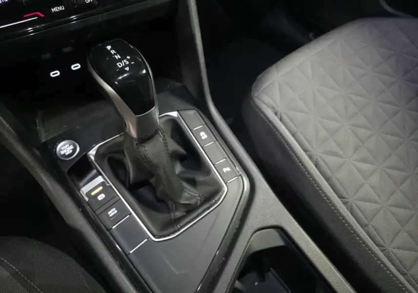 Gros plan sur la console centrale du Volkswagen Tiguan 2023 avec levier de vitesse automatique et sellerie tissu grise.