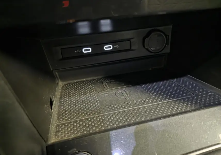 Gros plan sur la console centrale du Volkswagen Tiguan gris 2023, montrant les ports USB-C et la zone de charge sans fil.