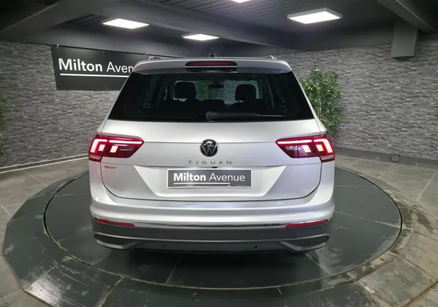 Vue arrière d'un Volkswagen Tiguan gris métallisé 2023 avec feux LED allumés dans un showroom.
