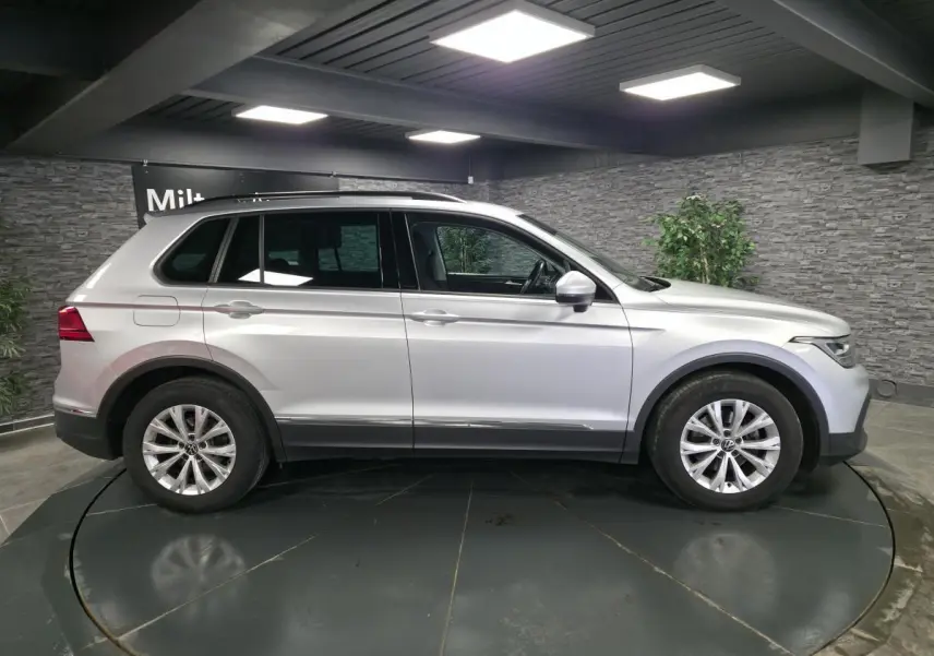 Profil droit d’un Volkswagen Tiguan gris métallisé 2023 en intérieur avec jantes alliage 17 pouces.