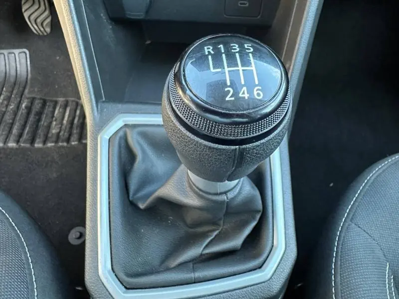 Gros plan sur le levier de vitesses manuel du Dacia Jogger 2025, entouré de sellerie noire et console grise.
