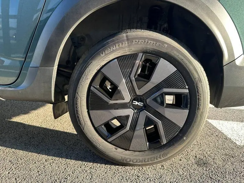 Gros plan sur la roue avant droite du Dacia Jogger Vert Cèdre métallisé avec jante noire au design géométrique.