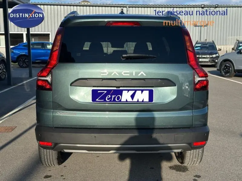 Vue arrière d'un Dacia Jogger 2025 vert cèdre métallisé avec feux arrière en L et lunette arrière surteintée.