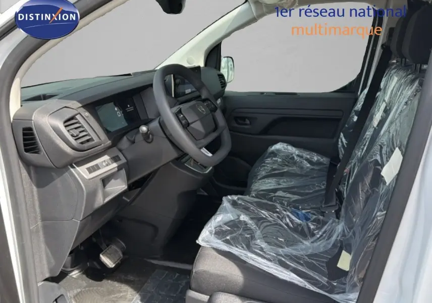 Vue intérieure côté conducteur du Citroën Jumpy blanc Kaolin, montrant le tableau de bord et les sièges protégés par des housses plastiques.