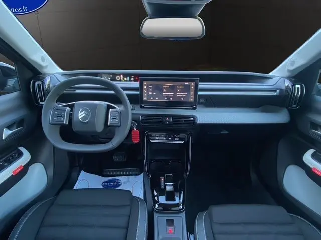 Vue intérieure avant du tableau de bord gris foncé de la Citroën C3 Hybrid 145 avec écran tactile central et volant multifonction.