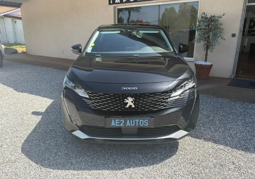 Vue de face d'un Peugeot 3008 noir 2021 avec calandre distinctive et logo lion visible sur un parking extérieur.