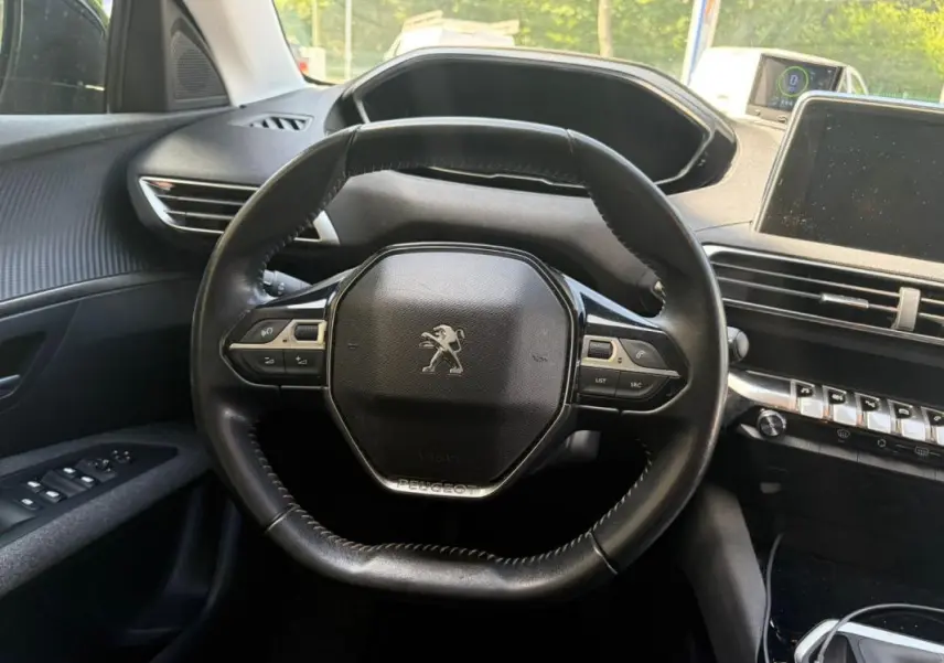 Vue intérieure centrée sur le volant noir du Peugeot 3008 2021 avec tableau de bord et commandes visibles.