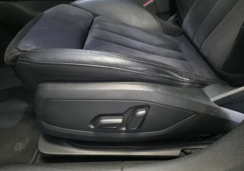 Gros plan sur le siège avant conducteur en cuir et Alcantara noir avec commandes électriques latérales dans l'Audi A4 Allroad gris.