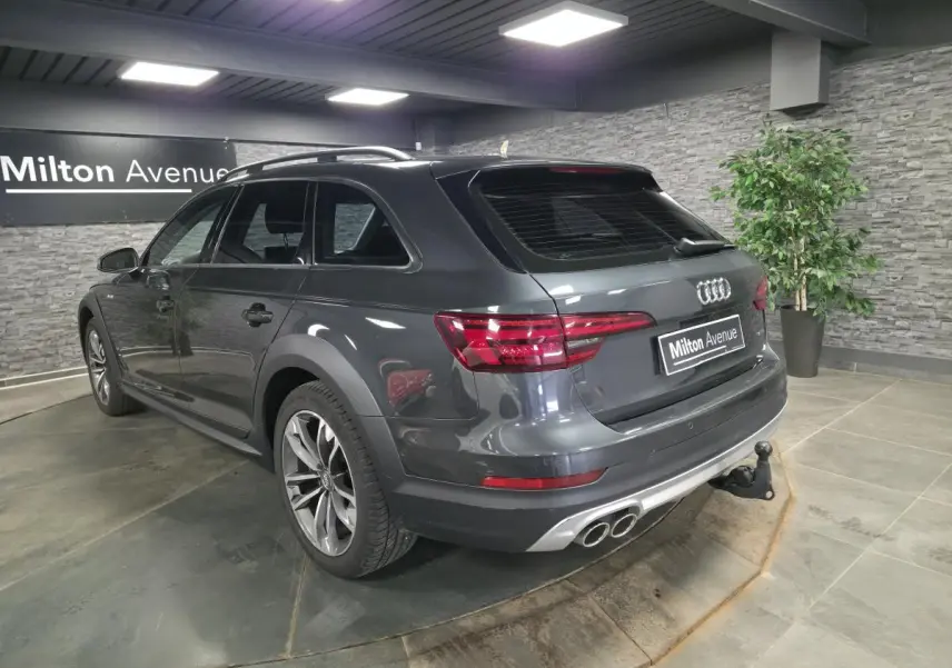 Audi A4 Allroad gris métallisé vue 3/4 arrière droit avec jantes 18 pouces et crochet d'attelage en intérieur showroom.