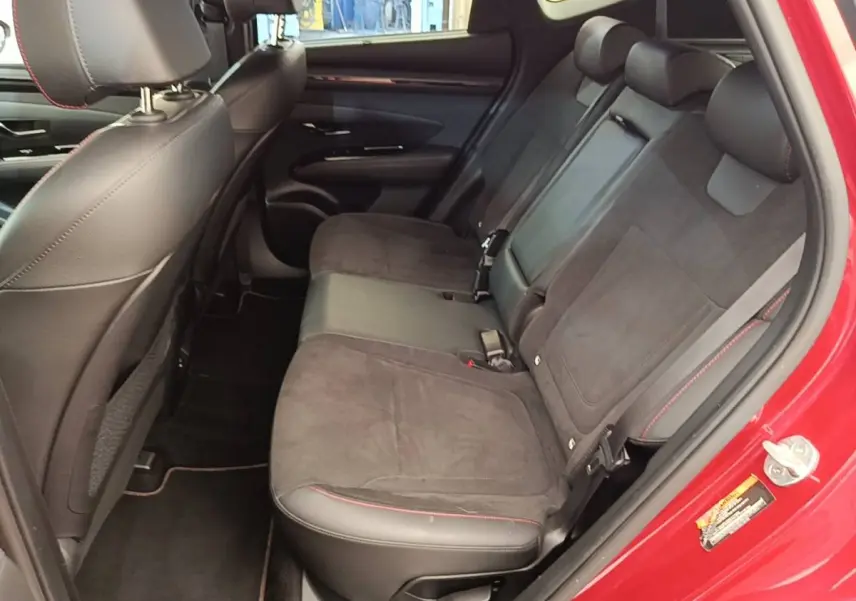 Vue intérieure arrière côté droit du Hyundai Tucson rouge 2022, sièges noirs avec surpiqûres rouges.