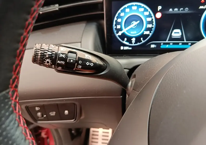 Gros plan sur la manette des feux et clignotants côté gauche du volant du Hyundai Tucson 2022, tableau de bord digital visible.