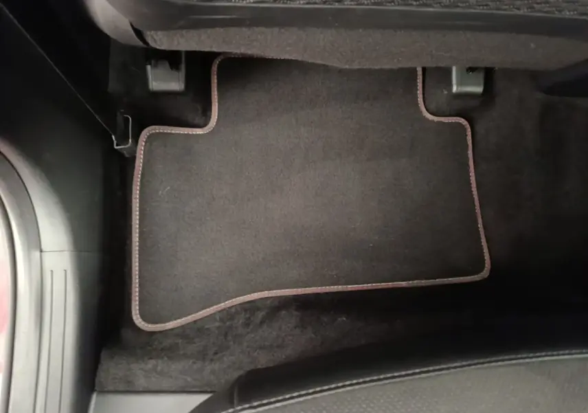 Tapis de sol noir avec surpiqûres rouges côté conducteur dans un Hyundai Tucson 2022 hybride diesel.