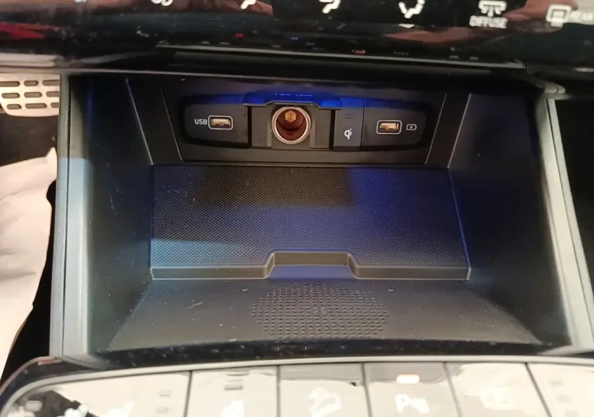 Gros plan sur la console centrale du Hyundai Tucson 2022, montrant ports USB, prise 12V et zone de recharge sans fil.